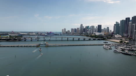 Vista-Aérea-De-Barcos-Frente-A-Los-Puentes,-Frente-Al-Horizonte-De-Miami,-Estados-Unidos