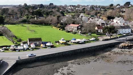 Close-circling-drone-shot-on-bright-day-of-Bordeaux-harbour-Guernsey-showing-roadside-and-boat-storage-and-views-over-fields-to-St-Sampson