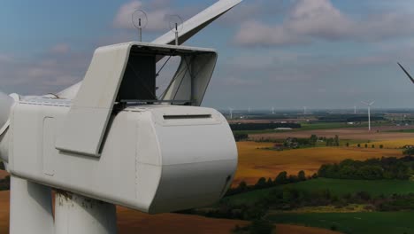 Wind-Turbine-Close-Up-Aerial-Shot-Panning-Around-the-Read-with-Farmland-in-the-Background