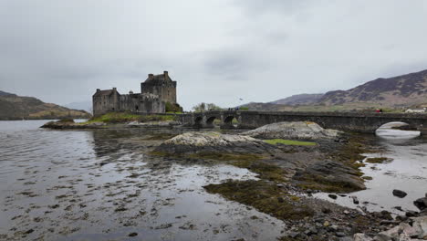 Historic-Eilean-Donan-Castle-by-a-misty-loch-and-arched-stone-bridge-in-Scotland