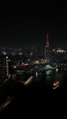 Atemberaubende-Nächtliche-Luftaufnahme-Von-Ho-Chi-Minh-Stadt,-Vietnam-Saigon-Mit-Den-Lichtern-Der-Stadt-Und-Der-Uferpromenade,-Vertikales-Video