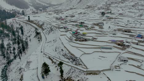 Drohnenaufnahmen-über-Dem-Dorf-Und-Den-Bunten-Häusern-über-Dem-Naltar-Tal-In-Gilgit,-Pakistan-Im-Winter-Mit-Schnee-Bedeckt