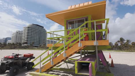 Farbenfroher-Rettungsschwimmerturm-Am-Miami-Beach-Mit-Palmen-Und-Hochhäusern-Im-Hintergrund