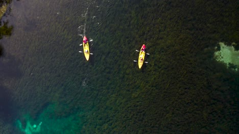Toma-Aérea-Siguiendo-Dos-Kayaks-Flotando-Por-El-Cristalino-Río-Rainbow.