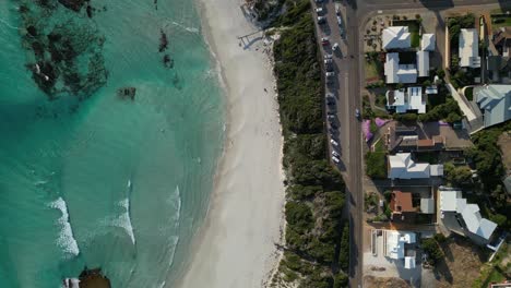 Top-down-split-aerial-view-above-the-middle-of-the-beach-and-the-residential-area-with-moving-cars,-drone