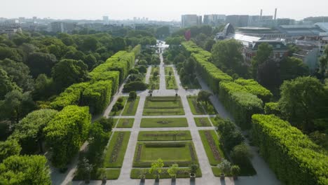 El-Jardín-Del-Museo-De-Historia-Natural-De-París-Con-Exuberantes-Senderos-Verdes-Y-Telón-De-Fondo-De-La-Ciudad,-Vista-Aérea