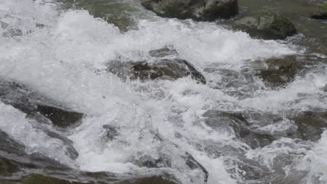 Close-up-of-bubbling-water-cascading-over-the-rocks-of-Goa-Rang-Reng-Waterfall-in-Bali,-Indonesia,-captured-in-slow-motion