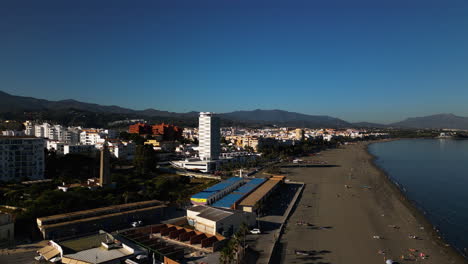 Sandy-beach-and-cityscape-of-Estepona,-aerial-drone-orbit-view