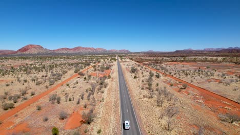 Vídeo-De-Drones-En-4k-Que-Sigue-A-Una-Caravana-Mientras-Conduce-Por-Una-Carretera-Muy-Larga-Y-Recta-En-El-Interior-De-Australia,-En-El-Territorio-Del-Norte