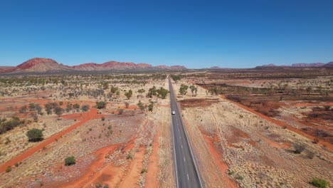 Vídeo-De-Drones-En-4k-Que-Sigue-A-Una-Caravana-Mientras-Conduce-Sola-Por-Una-Carretera-Muy-Larga-Y-Recta-En-El-Interior-De-Australia,-En-El-Territorio-Del-Norte