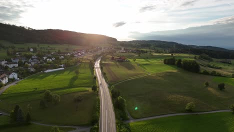 A-scenic-aerial-view-of-a-road-cutting-through-lush-green-fields-in-Greifensee,-Switzerland