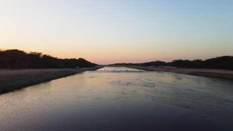 Aerial-view-rising-over-a-shallow-river,-serene,-sunny-evening-in-Saudi-Arabia