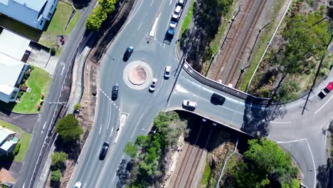 Schwenk-über-Landschaft-Autos-Fahren-Um-Kreisverkehr-Hauptstraße-Straße-Mit-Bahnlinie-Brücke-Infrastruktur-Transport-Ourimbah-Australien-Drohne-Luftaufnahme