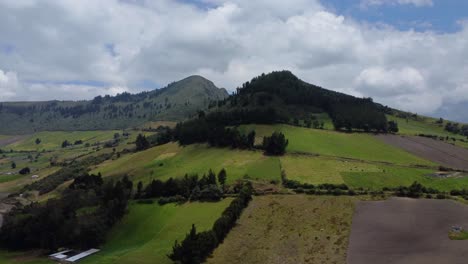Aerial-Drone-Ascending-Shot-Of-Farms-And-Forested-Mountain-Peaks