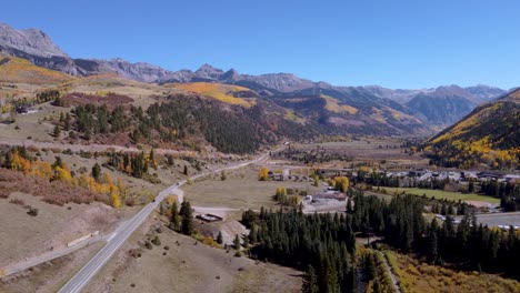 Vista-Aérea-De-La-Autopista-Del-Millón-De-Dólares-Que-Corre-Hacia-Silverton-Colorado-Con-álamos-Dorados-Que-Bordean-Las-Montañas-Rocosas-En-Un-Día-Despejado