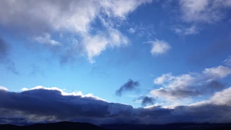 flight-with-a-drone-in-the-Tietar-valley,-province-of-Avila,-one-afternoon-with-a-blue-sky-and-low-clouds-hanging-on-the-mountains-that-appear-dark-in-the-light-of-the-sunset,-Spain