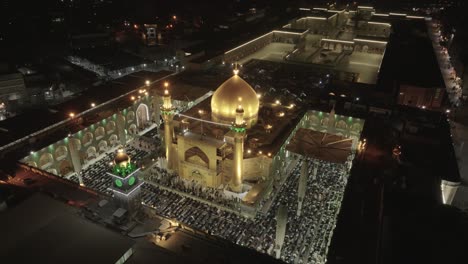Drone-shot-of-Imam-Ali-Holy-Shrine-in-Iraq-during-prayer,-capturing-the-serene-ambiance,-worshippers-gathered,-and-intricate-architecture-bathed-in-soft-light