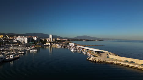 Pier-of-Estepona-city-and-skyline-in-horizon,-aerial-ascend-view