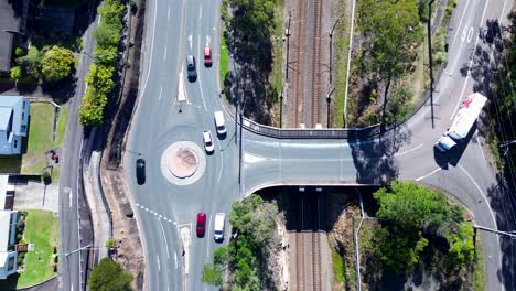 Landscape-view-of-cars-vehicles-driving-around-roundabout-and-truck-over-train-railway-bridge-transport-traffic-infrastructure-Ourimbah-Australia-drone-aerial