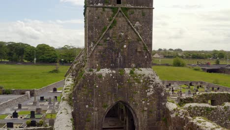 Luftumlaufbahn-Um-Den-Alten-Verwitterten,-Moosbedeckten-Turm-Des-Klosters-Claregalway,-Während-Vögel-Herumfliegen