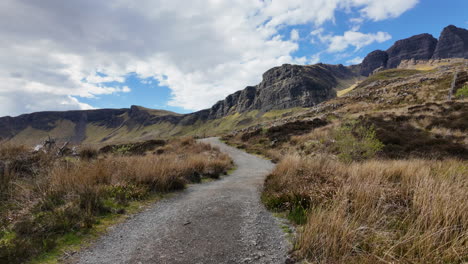 Hiking-trail-in-Isle-of-Skye-with-stunning-rocky-cliffs-and-lush-greenery-under-a-blue-sky