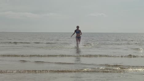 Teenage-girl-running-fast,-bikini,-ocean-water,-sunlight,-slow-motion