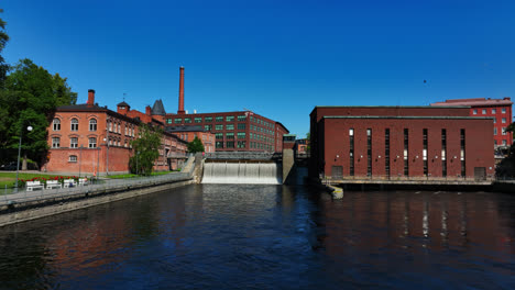 Aerial-view-approaching-the-Tammerkoski-dam,-sunny,day-in-Tampere,-Finland