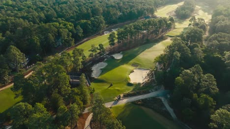 Wunderschöne-Luftaufnahme-Eines-Golfplatzes-Bei-Sonnenaufgang,-Während-Das-Platzpersonal-Die-Grüns-Rollt