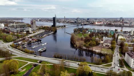 Drone-Aéreo-Volar-Paisaje-Del-Río-Zunds,-Tráfico-Callejero-En-La-Capital-De-Letonia-Riga