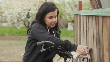 European-Woman-Wiping-Handlebar-Of-Bicycle-Using-Cloth