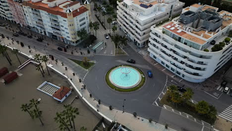 Rotonda-Con-Fuente-Y-Edificios-De-La-Ciudad-De-Estepona,-Vista-Aérea-De-Drones