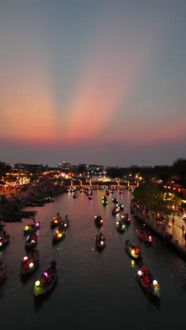 Beautiful-sunset-aerial-over-lantern-boats-full-of-tourists-at-the-beautiful-Hoi-An-lantern-celebration,-vertical-video