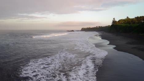Balian-surfers-beach,-waves-swelling-along-the-shoreline-in-the-soft-early-morning-sun-light