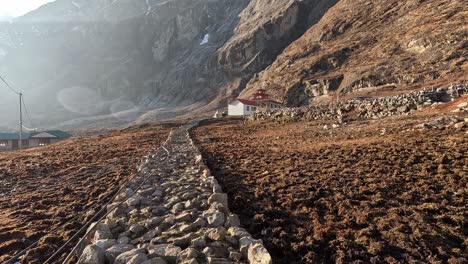 Walking-over-a-rocky-path-towards-the-monastery-of-Langtang-village-in-Langtang-Valley,-Nepal