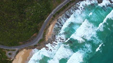 4K-drone-birds-eye-view-of-a-camper-van-driving-along-the-Great-Ocean-Road-in-Victoria,-Australia