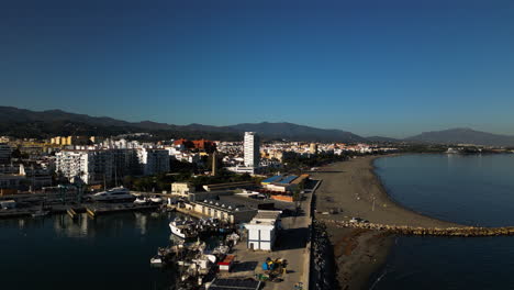 Coastal-cityscape-of-Estepona-with-sandy-beach-and-mountain-in-horizon,-aerial-view