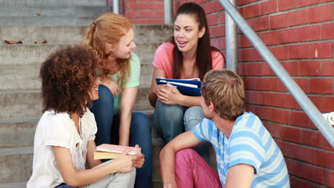 Happy-students-sitting-on-steps-chatting