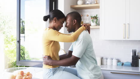 A-diverse-couple-hugs-in-kitchen,-sharing-tender-moment