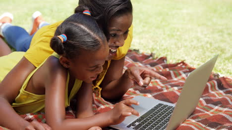 Portrait-of-mother-and-daughter-are-using-a-laptop-in-the-garden-
