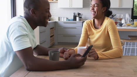 African-American-couple-enjoys-a-moment-in-the-kitchen,-drinking-coffee