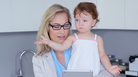 Mother-holding-baby-and-using-tablet