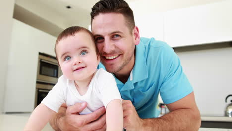 Smiling-father-lying-on-floor-with-his-baby-boy-