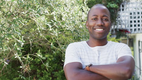 A-cheerful-African-American-man-stands-outdoors,-arms-crossed,-with-copy-space