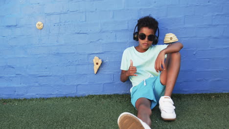 En-Un-Ambiente-Escolar,-Un-Niño-Afroamericano-Se-Relaja-Contra-Una-Pared-Azul-Con-Espacio-Para-Copiar