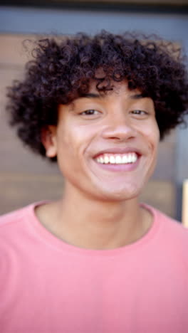 Vertical-video:-A-young-biracial-person-is-smiling-broadly,-blurred-background