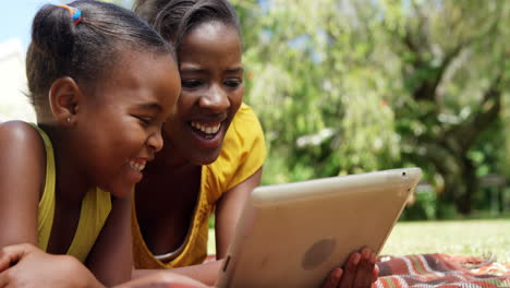 Portrait-of-cute-mother-and-daughter-are-using-a-tablet-in-the-garden-