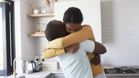 Una-Pareja-Afroamericana-Comparte-Un-Cálido-Abrazo,-Abrazándose-En-Una-Cocina.