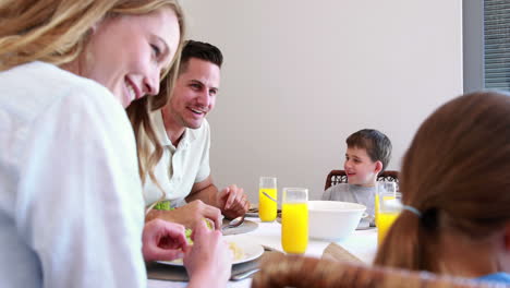 Familia-Joven-Feliz-Hablando-En-La-Mesa