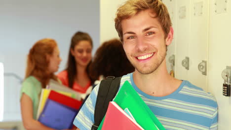 Handsome-student-leaning-on-locker-smiling-at-camera