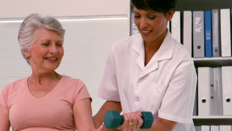 Physiotherapist-helping-patient-lift-hand-weight